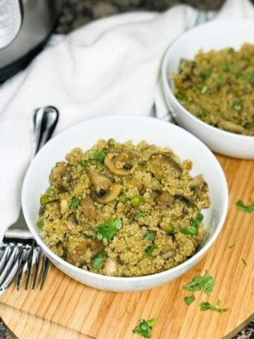 A bowl is with mushroom quinoa and placed on the wooden serving tray
