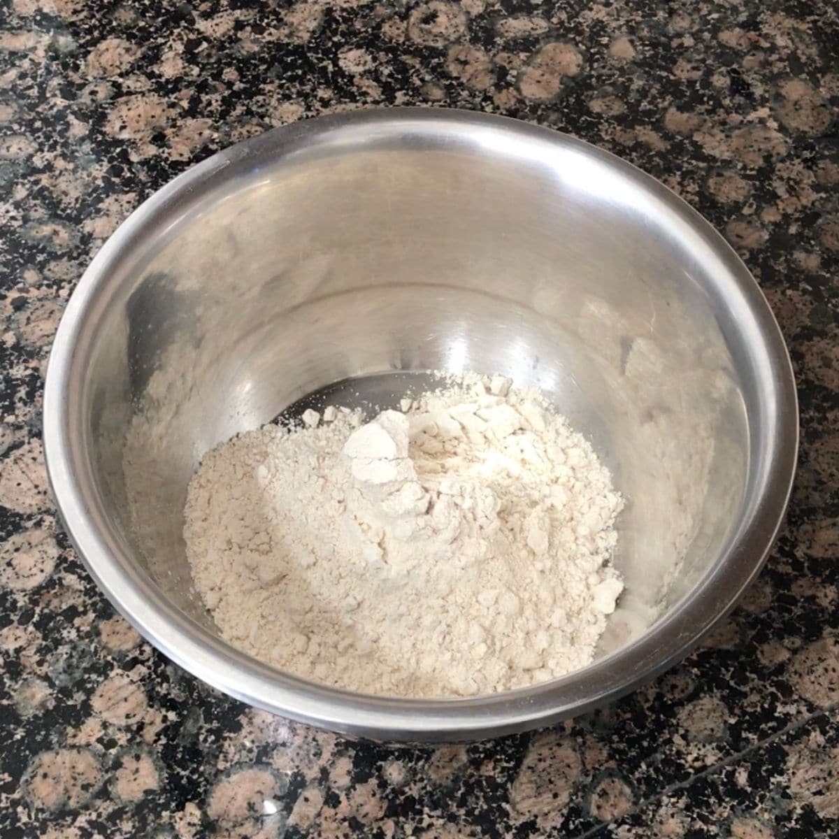 A vessel is filled with wheat flour, salt and placed on the counter top