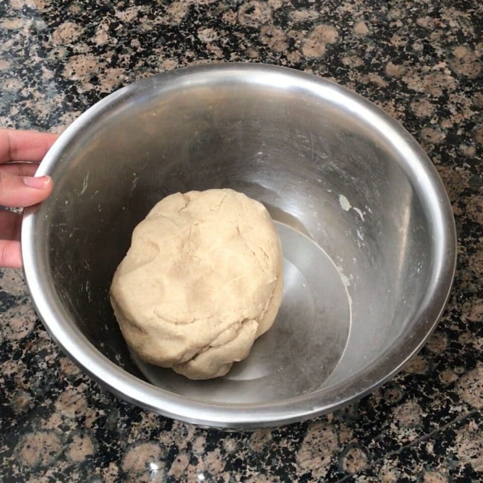 A steel bowl is with roti dough and is on the counter top.