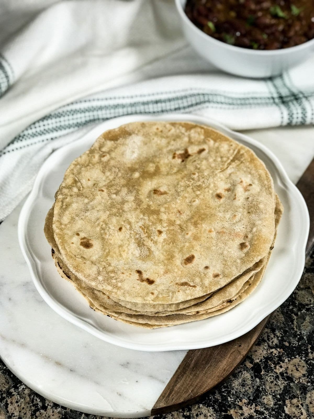 A plate of phulka roti is on the white serving board