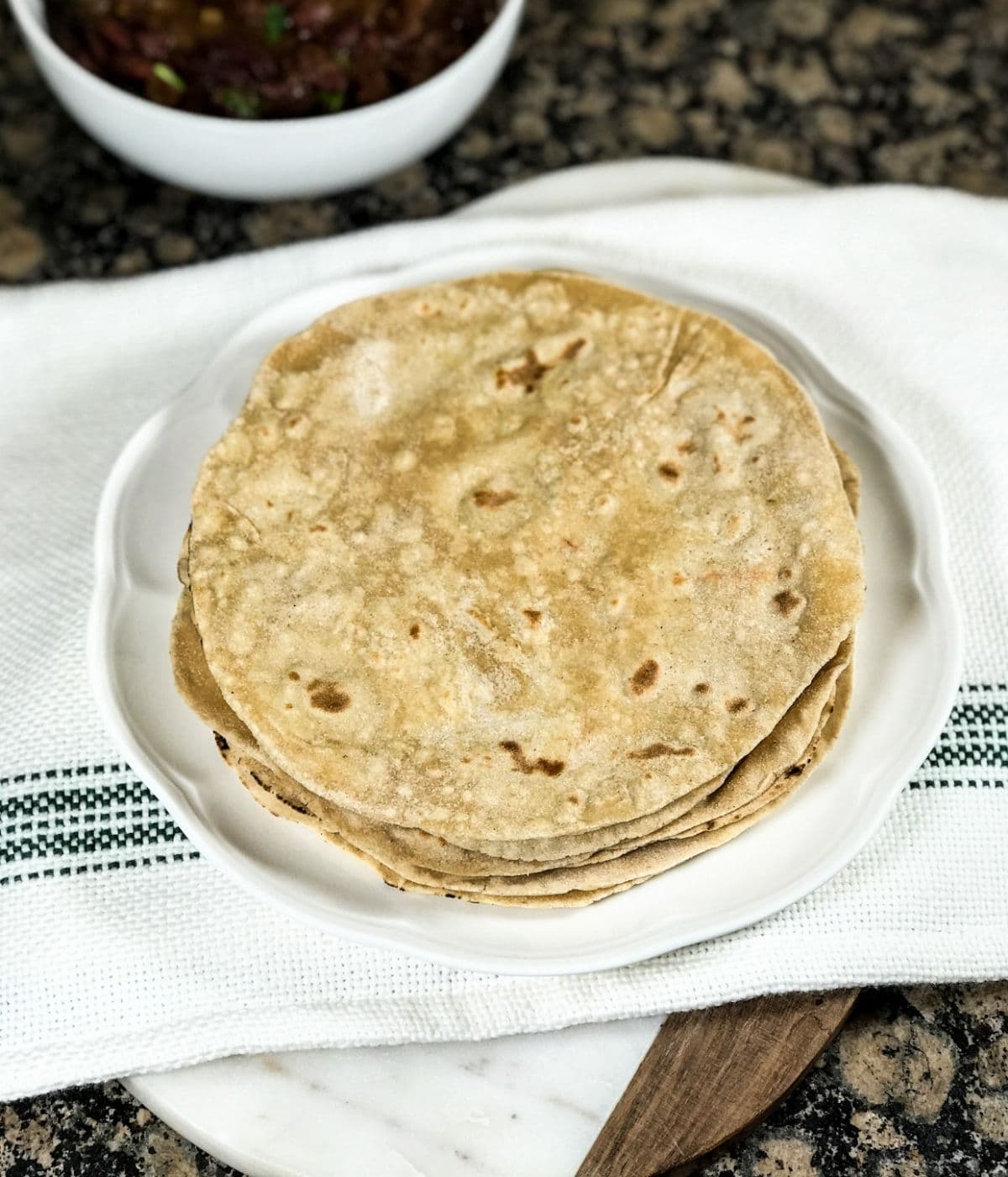 A plate of phulka roti is placed on the table along with curry