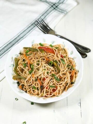 A plate is with hakka noodles over the white table
