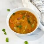 A bowl is with Instant pot vegetable sambar on the table.