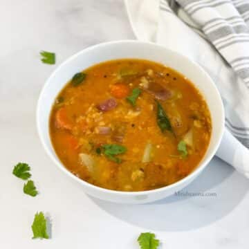 A bowl is with Instant pot vegetable sambar on the table.