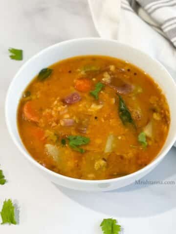 A bowl is with Instant pot vegetable sambar on the table.