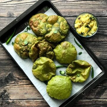 A tray is filled with Palak Puri and two kids are reaching out to take those puris