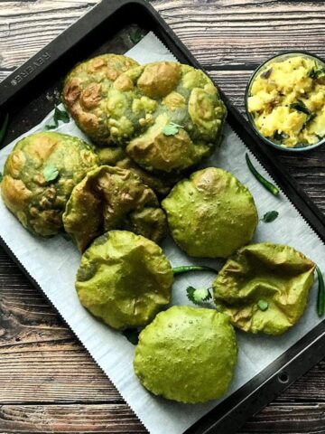 A tray is filled with Palak Puri and two kids are reaching out to take those puris