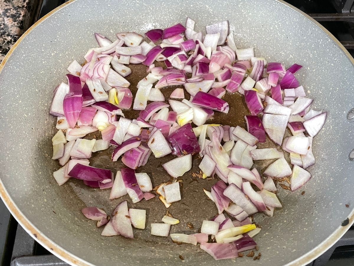 A pan is with oil and chopped onions over the heat