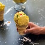 A girl hand is holding mango ice cream on cone