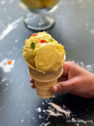 A girl hand is holding mango ice cream on cone