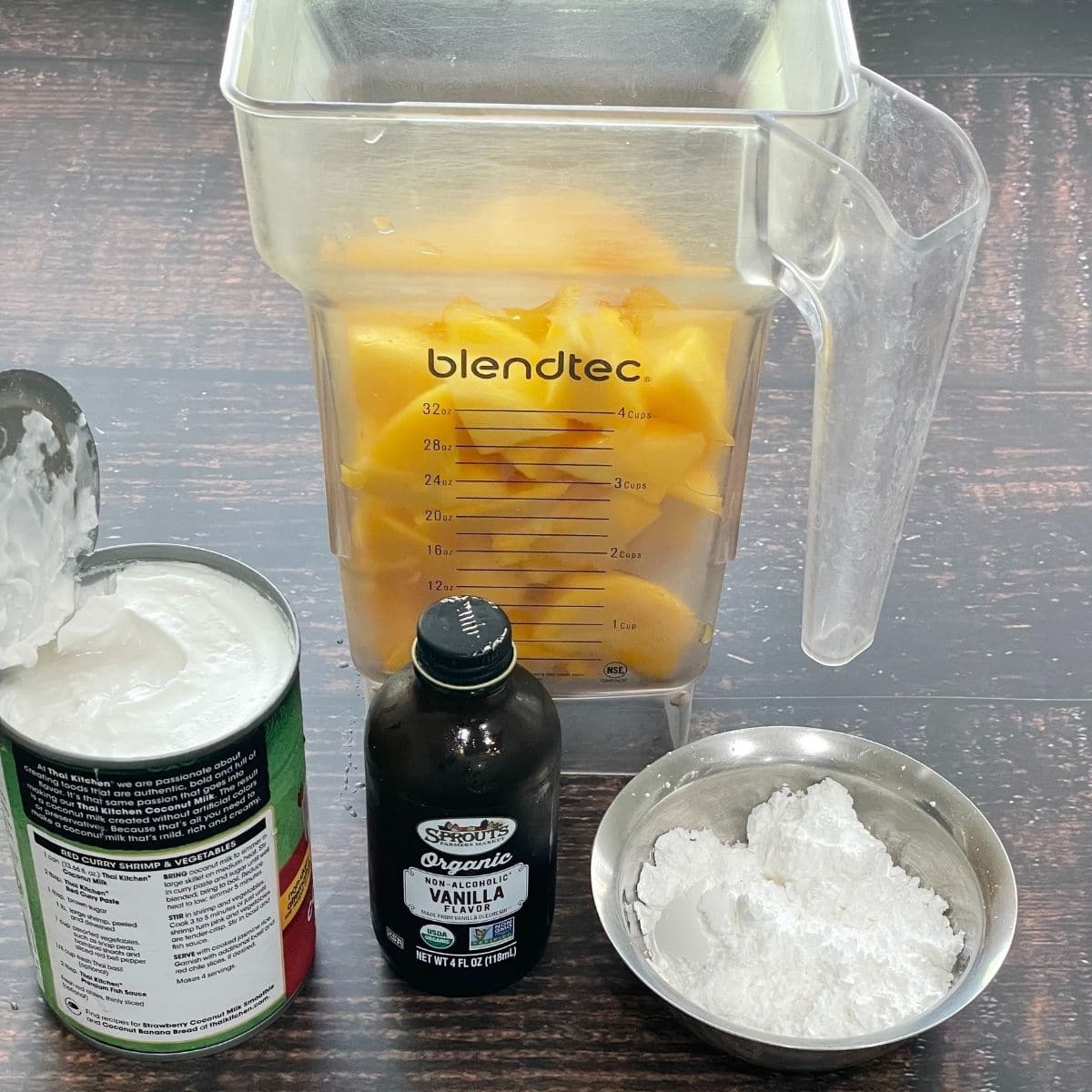 Mango ice cream ingredients are on the table like chopped mangoes, coconut milk and vanilla extract