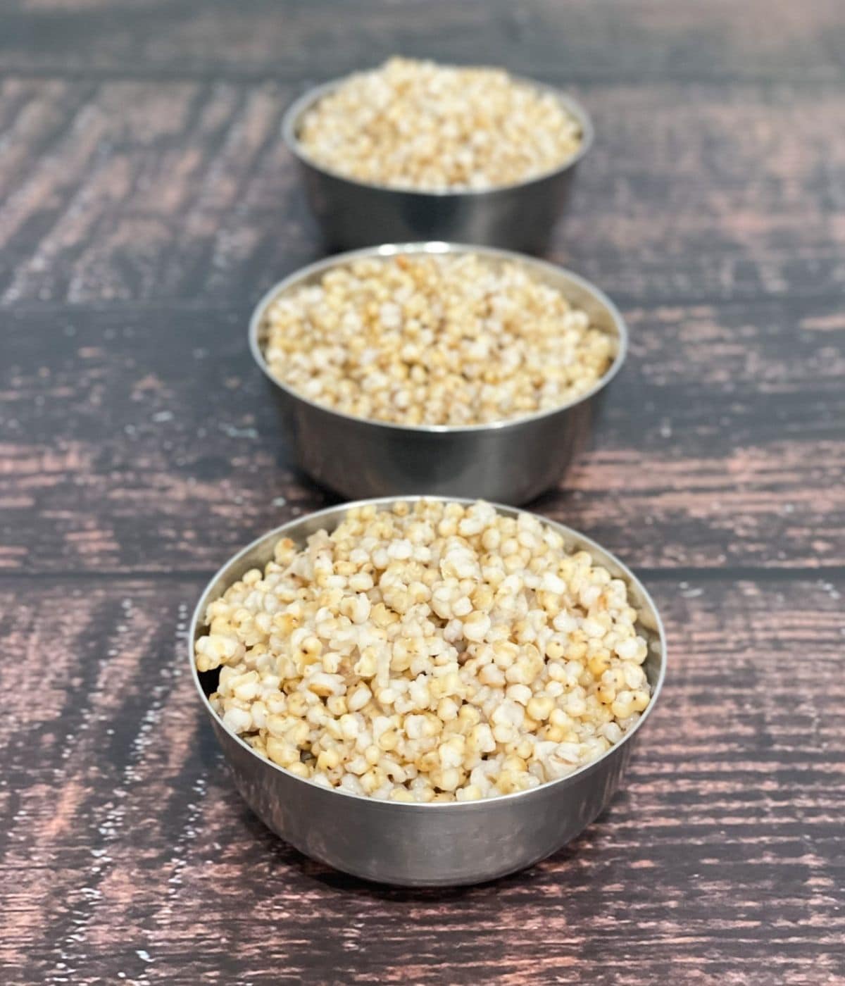 A stain less steel bowls are filled with cooked sorghum millet.