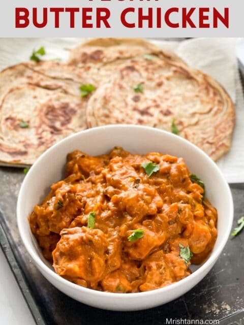 A white bowl is filled with vegan butter chicken and topped with cilantro