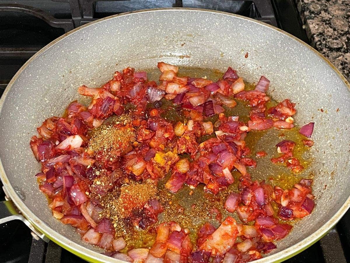 A pan is with spices for curry and over the stove top