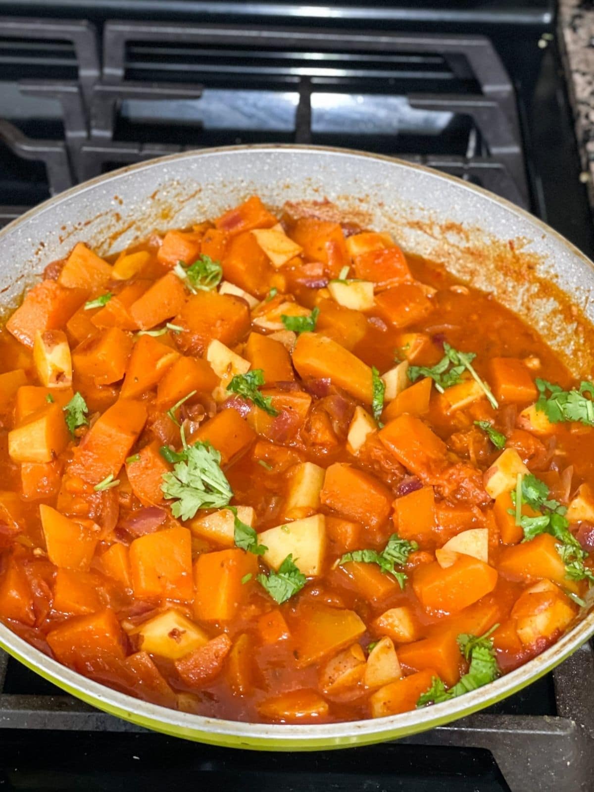 A pan is filled with pumpkin curry and over the heat