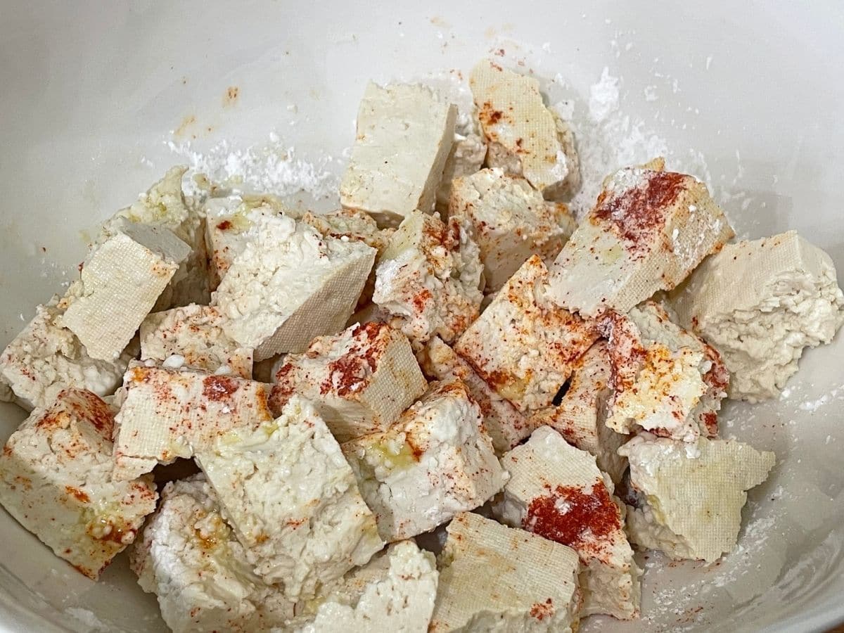 A bowl is filled with tofu, oil and red chili powder