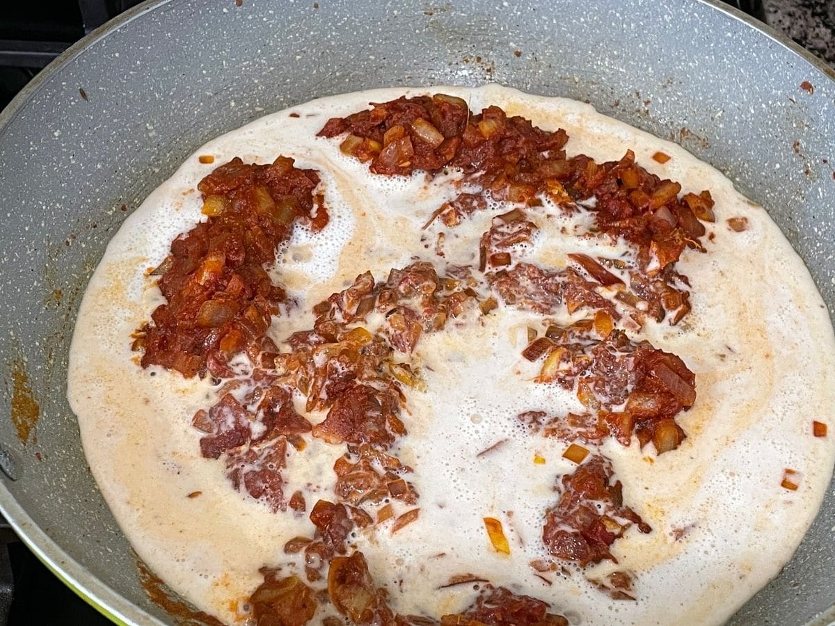 A pan is over the heat and cooking butter chicken curry