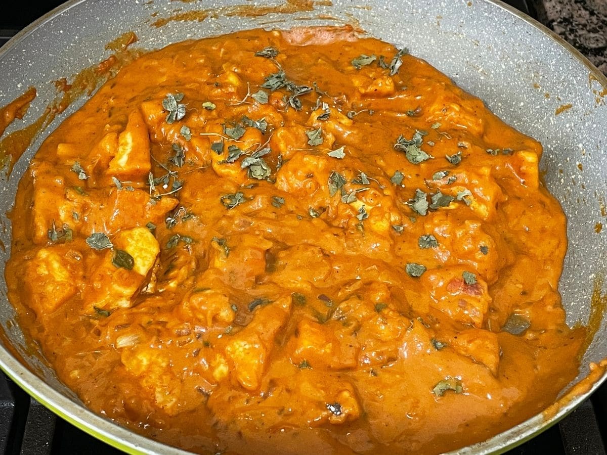 A pan of butter chicken curry on the stove top.