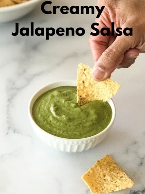 A man is dipping to jalapeno salsa with chips