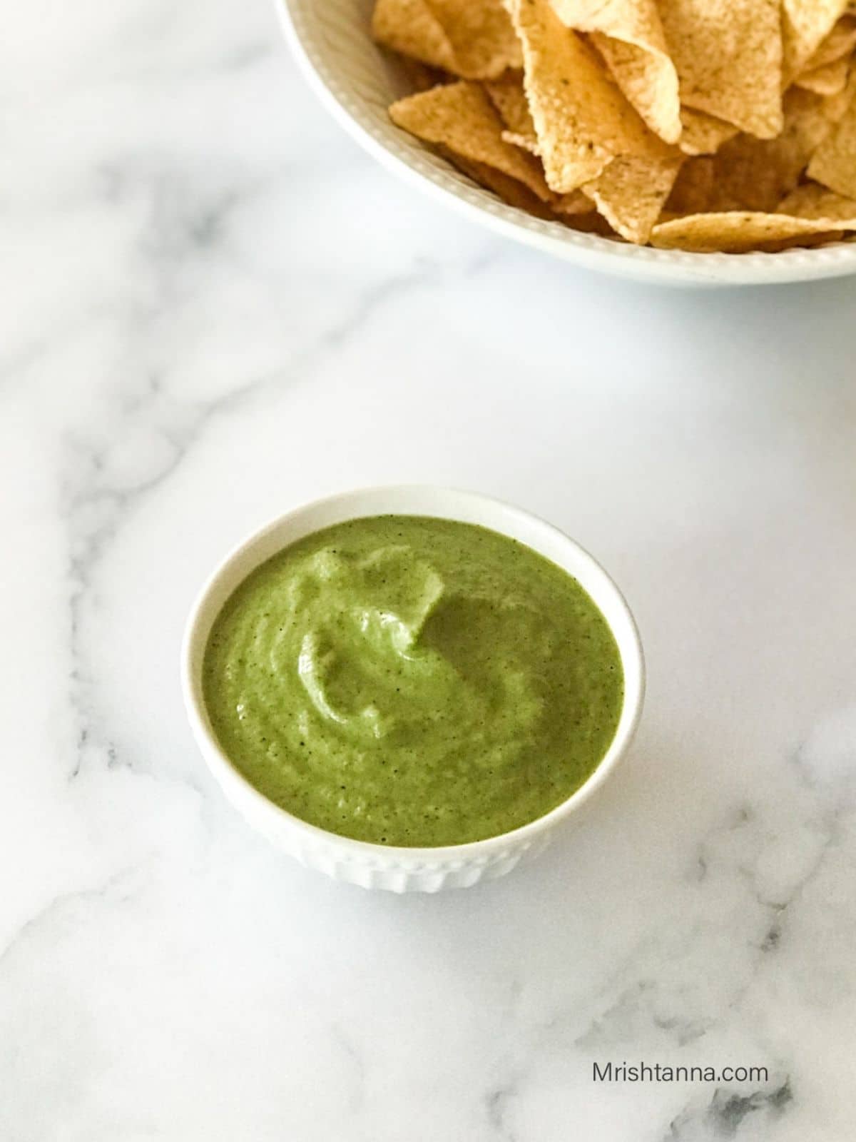 A bowl of jalapeno salsa is on the table.