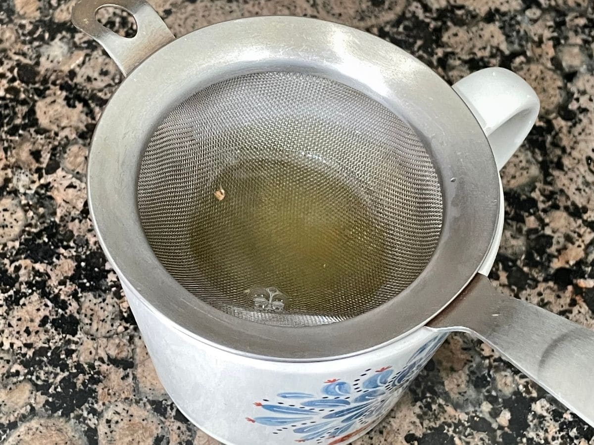 A cup with strainer is on the counter top.