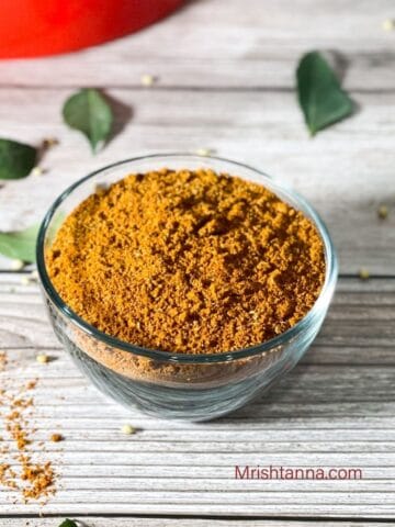 A glass bowl is filled with rasam powder mix.