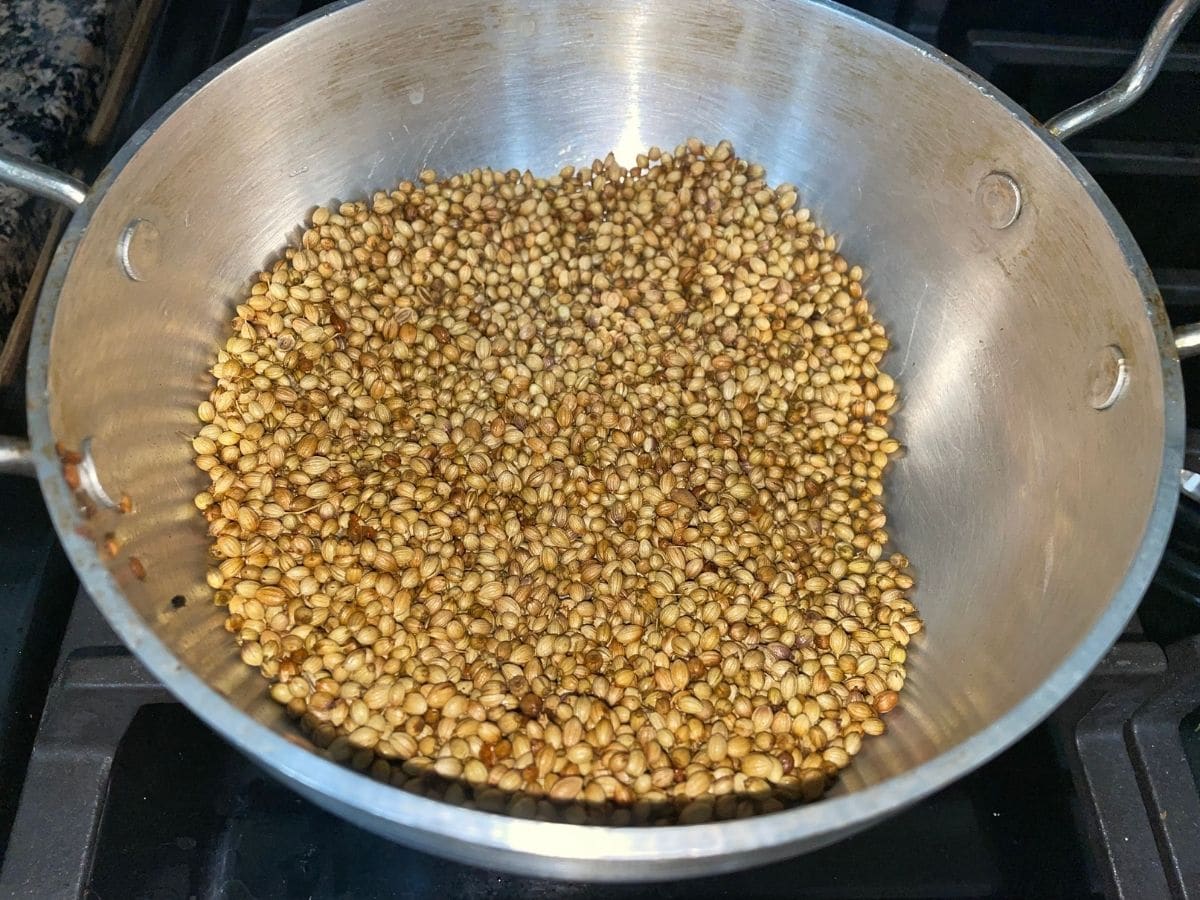 A pan is with coriander seeds over the heat