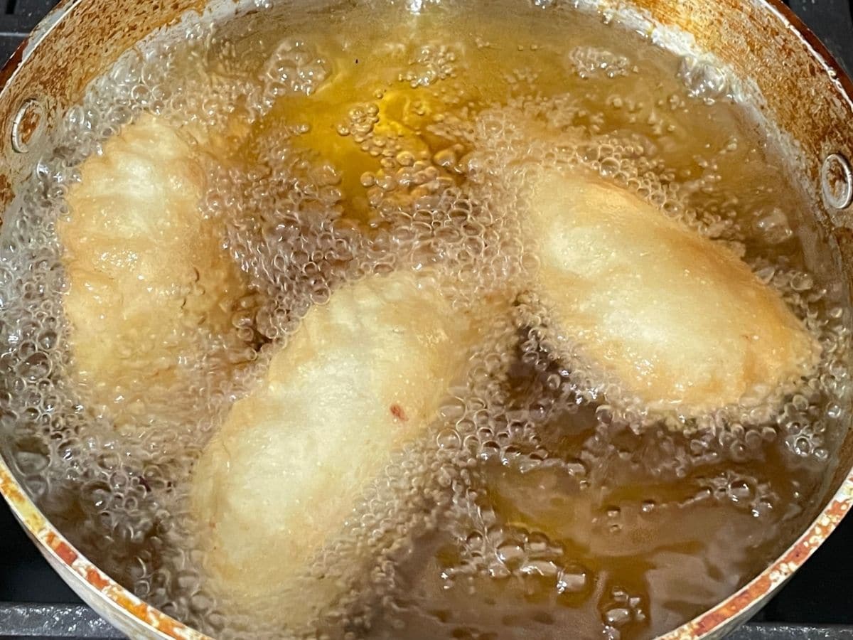A pot is with hot oil and dipped with karjikai over the heat.