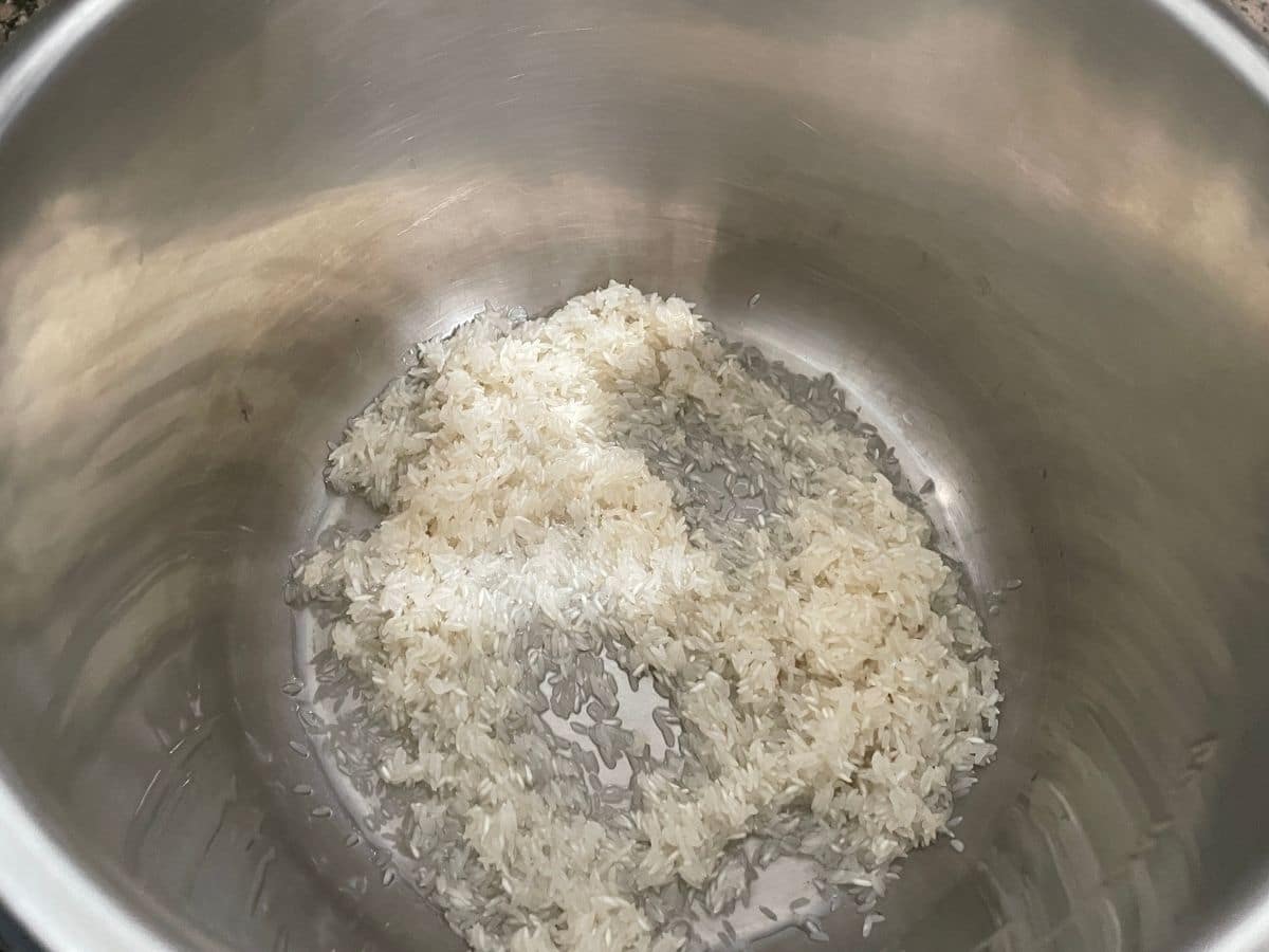 An instant pot is with rinsed rice.