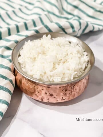 A small pot is filled with Sona masoori rice and placed on the white table.