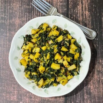 A plate is filled with Swiss chard and potato stir fry.