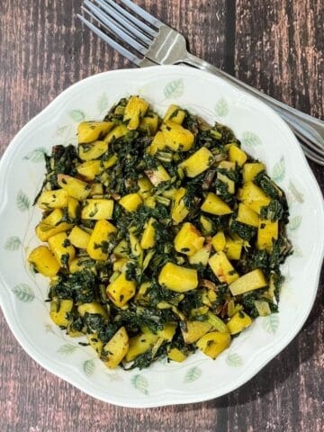 A plate is filled with Swiss chard and potato stir fry.