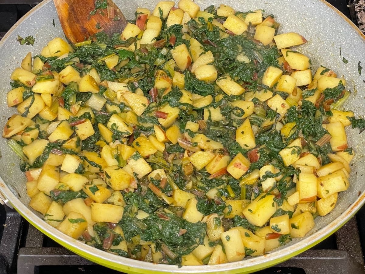 A pan is filled with cooked Swiss chard and potatoes