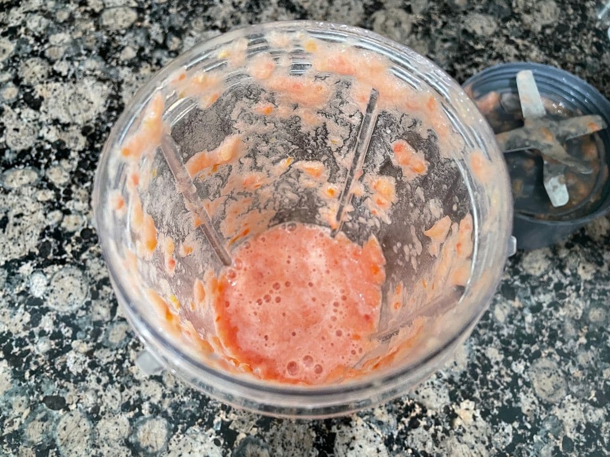A blender is with tomato puree on the counter top.