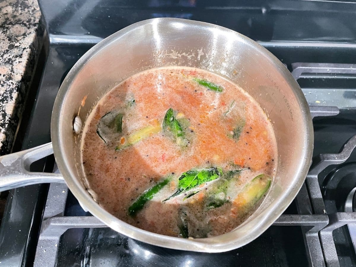 A pot is with pepper rasam over the heat