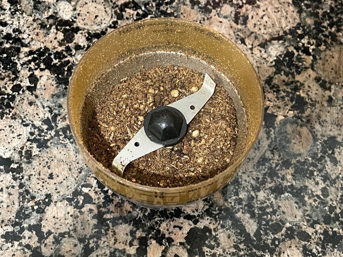 Grounded black pepper and cumin seeds are inside the coffee blender.