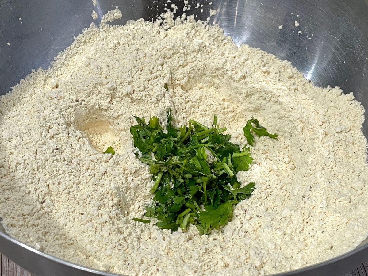 a bowl of flour is with cliantro and green chilies