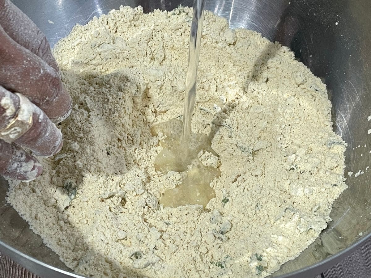 a man is mixing the flour with water for besan roti dough