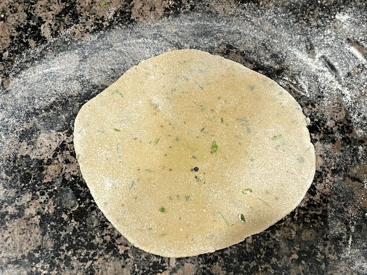 a rolled besan roti dough is on the counter top