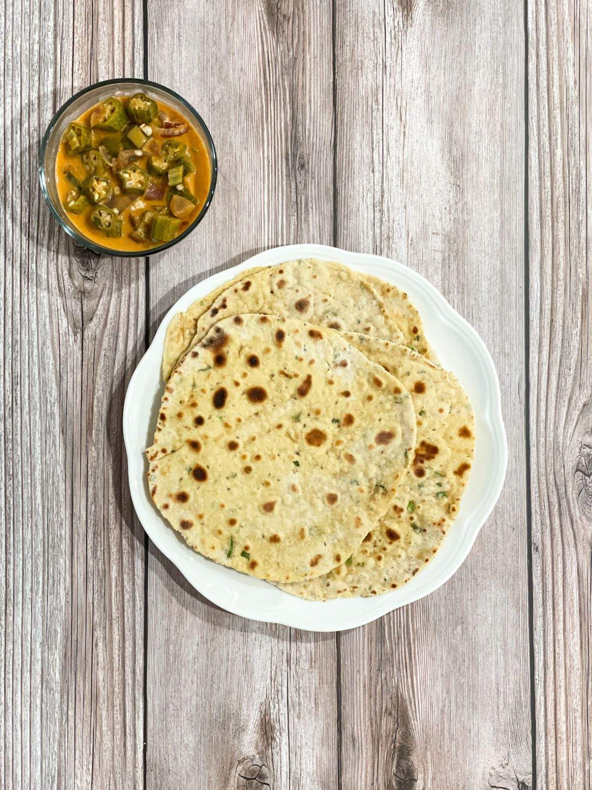 A plate is with besan rotis on the table along with bowl of curry.