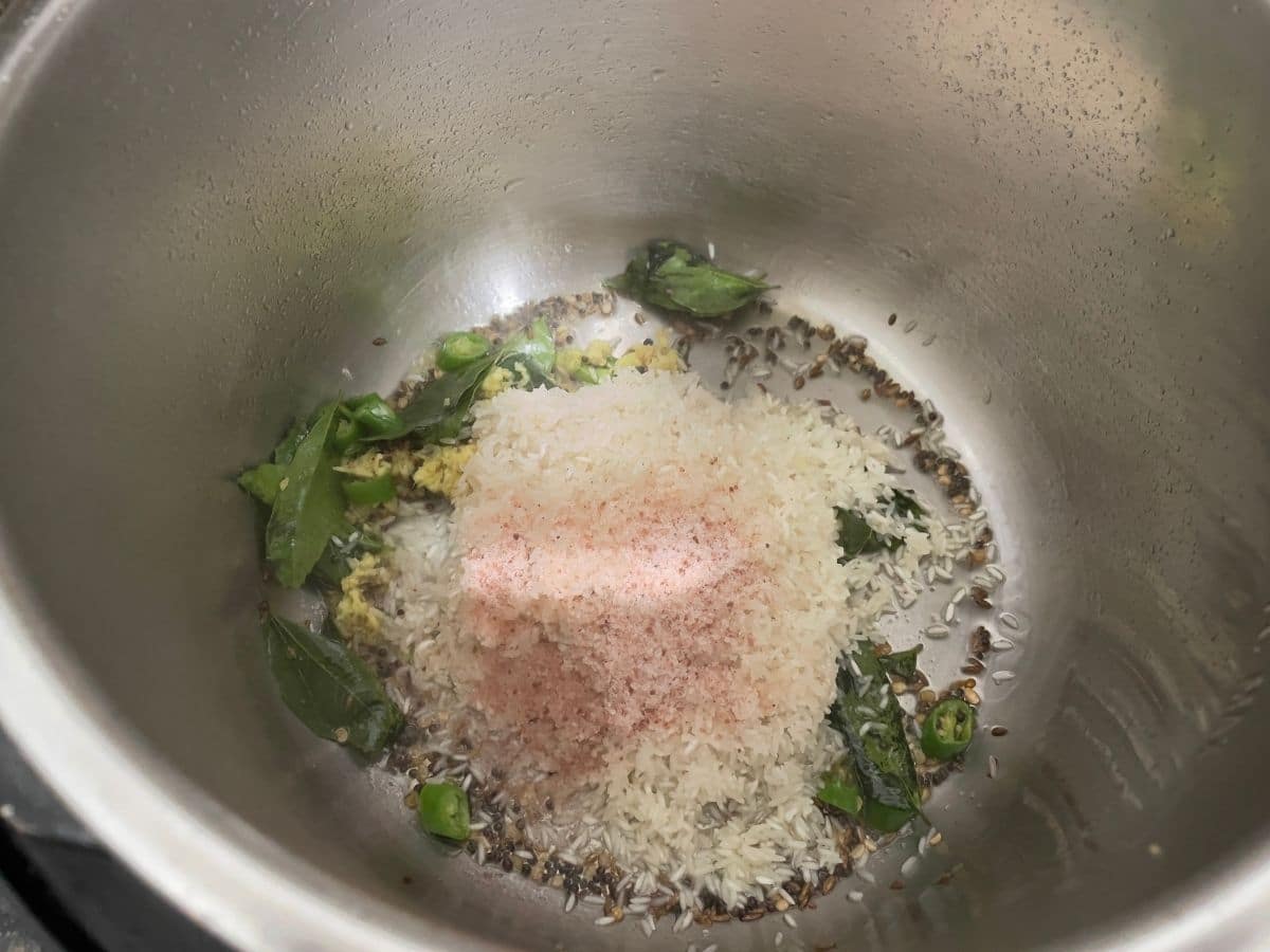 A pot is with rice and spices to make coconut rice.