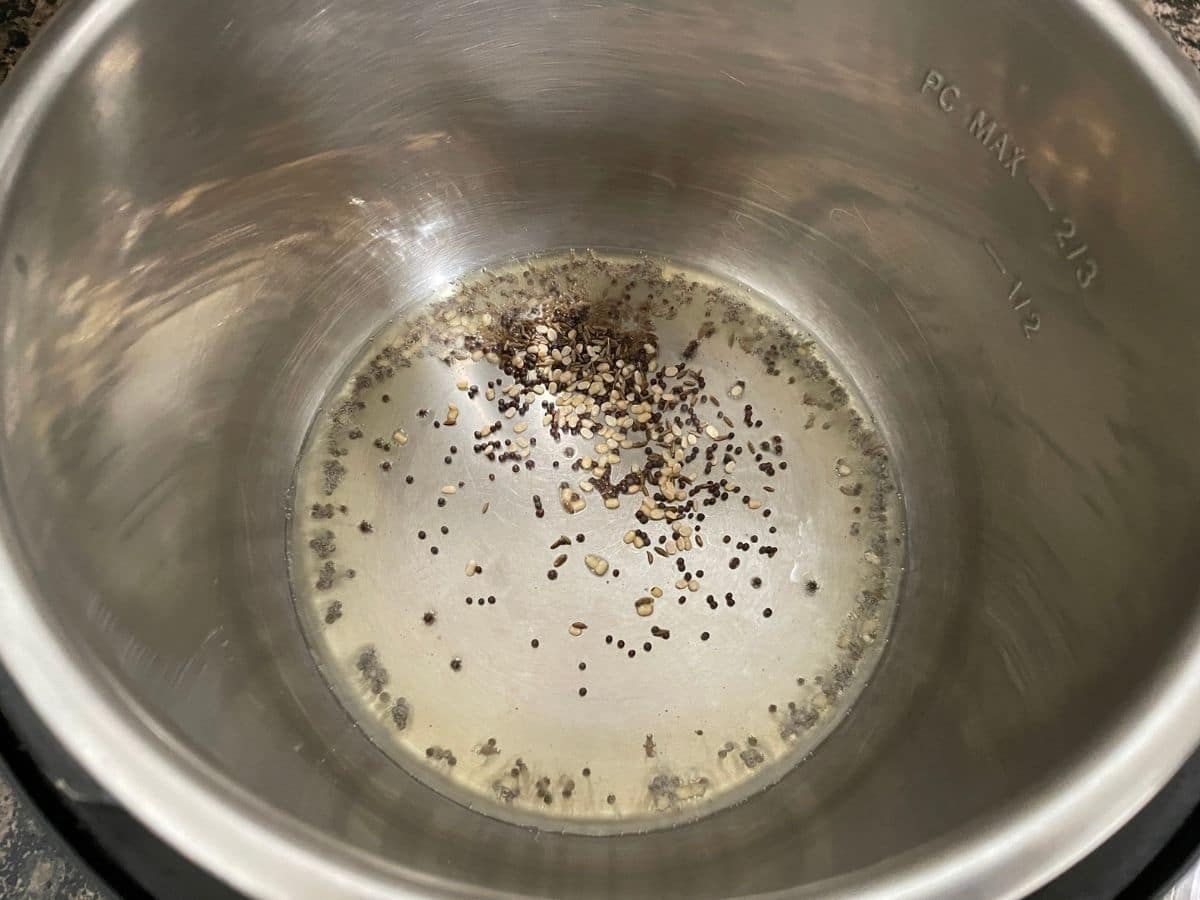 An instant pot is with oil and spices.