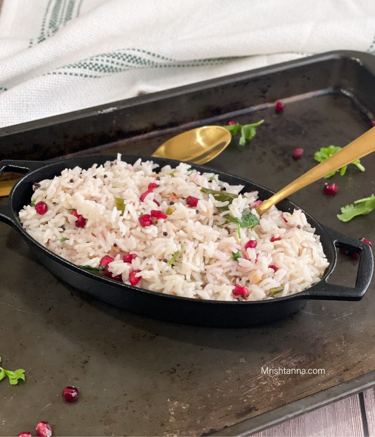 A bowl of coconut rice is on the tray along with golden spoons.