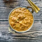 A copper bowl is with potato kurma and placed it on the table.