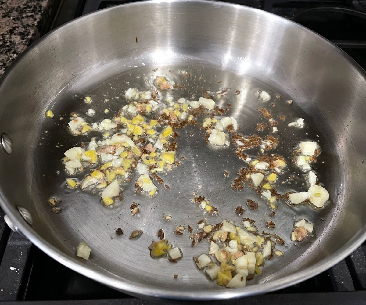 a pan is with oil, garlic and ginger over the heat.