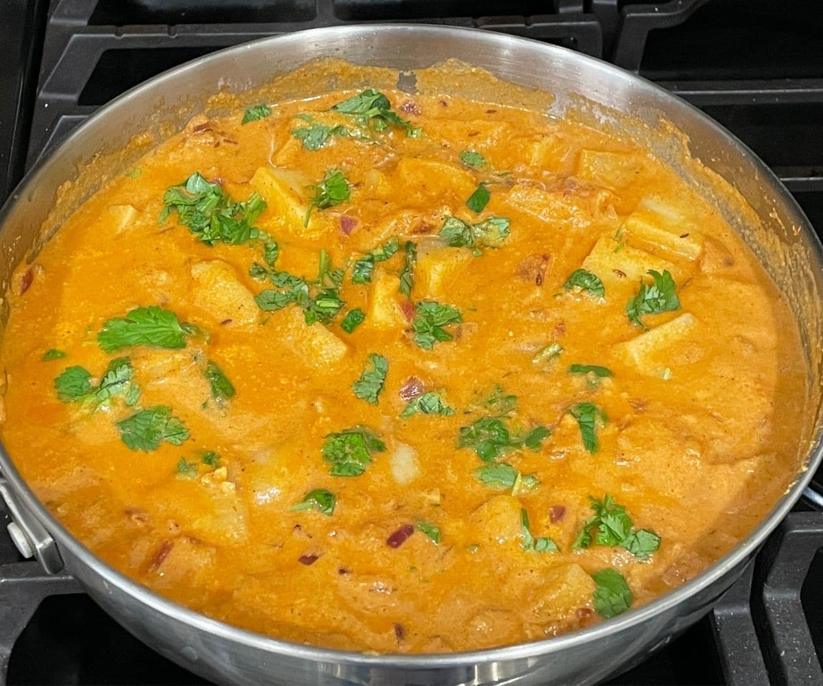 A pan full of potato kurma is garnished with cilantro.