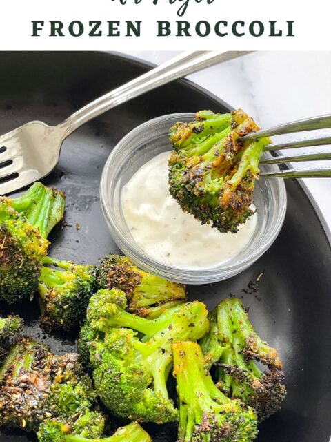 A plate of air fryer broccoli is on the table with vegan ranch dressing.