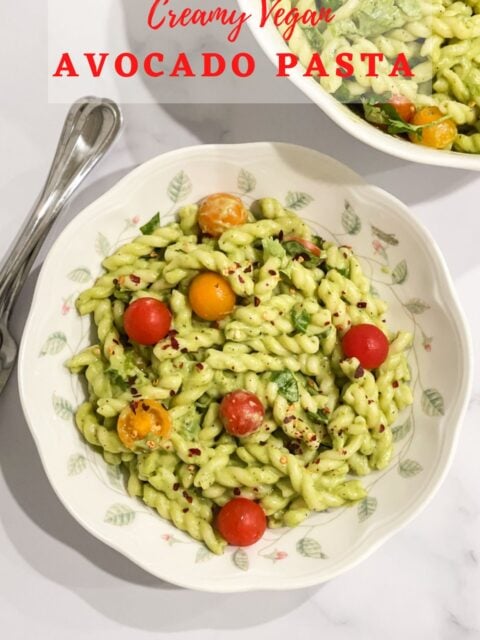 Close up of vegan avocado pasta with cherry tomatoes on top.