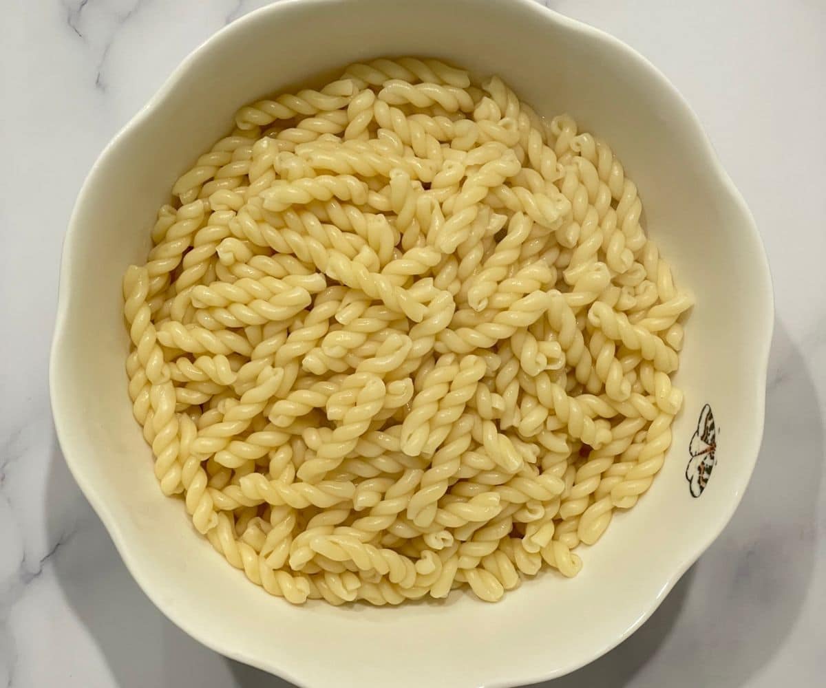 A medium sized bowl is with cooked pasta.