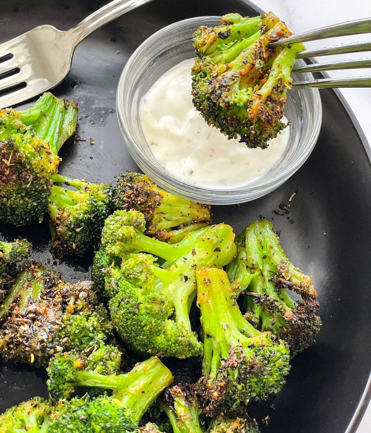 A fork is holding air fried broccoli with vegan ranch.